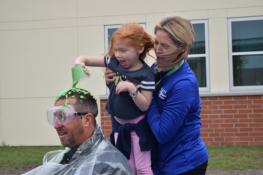 Principal Todd Richardson winces as kindergartner Hadley Smith dumps a cup of slime on him while Kristin Pomeroy, Parent-Teacher Organization president, holds her up.