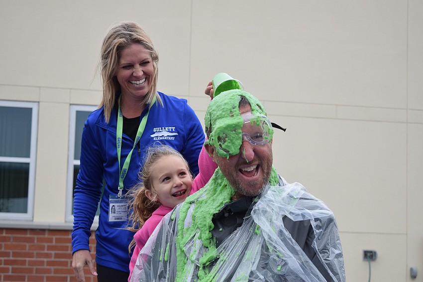 Kristin Pomeroy, Parent-Teacher Organization president, watches as kindergartner Cazlyn Davidson laughs while pouring slime on Principal Todd Richardson.