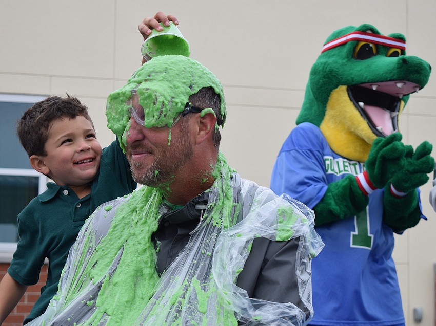 Kindergartner William Rasulo dumps slime on Principal Todd Richardson's head while Chompy, the school's mascot, cheers.