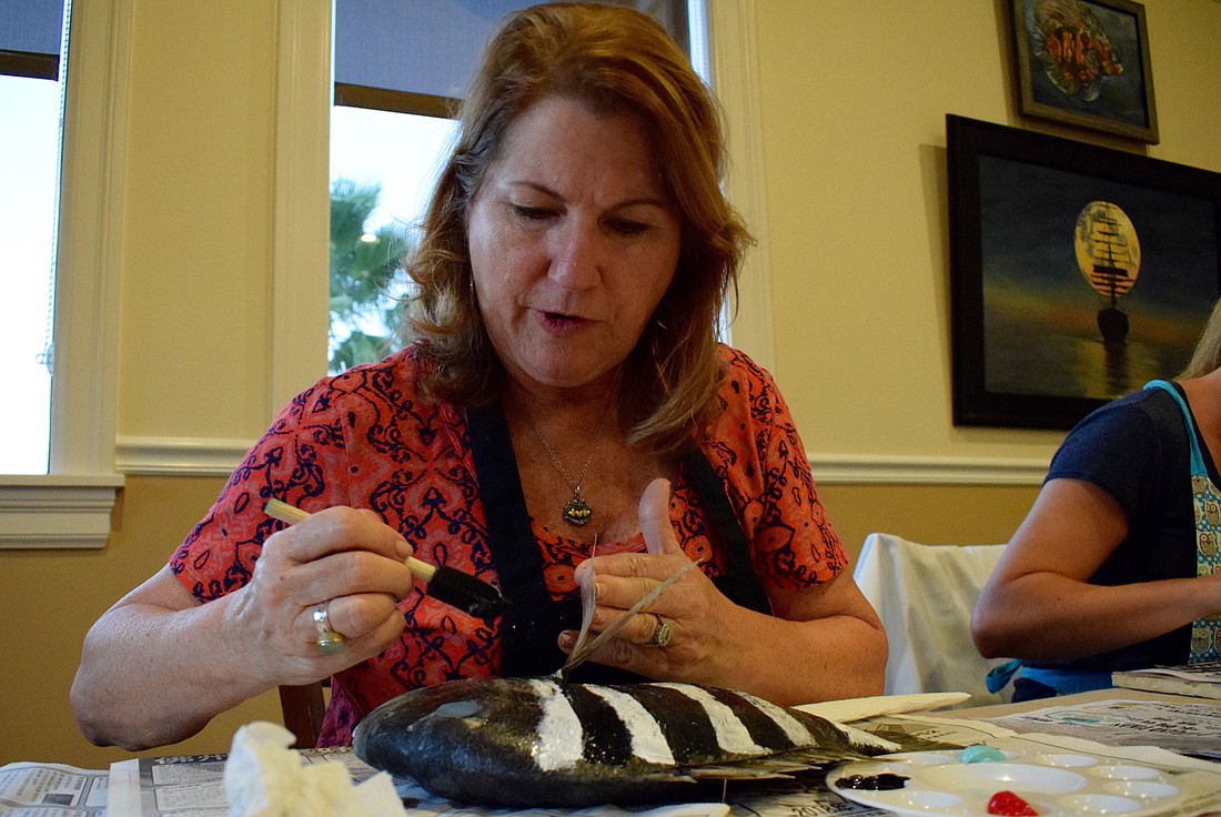 Terry Wilson, a Waterlefe resident, paints stripes on her sheepshead fish. "I was shocked when I found out we were painting with a real fish," Wilson says. "It sounds like fun."