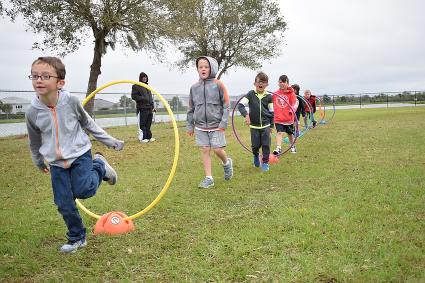 First graders Grant Spoonmore, Tristan Epting, Liam Durbal and James Droge run through Hula Hoops, which was one of the obstacles at the walkathon.
