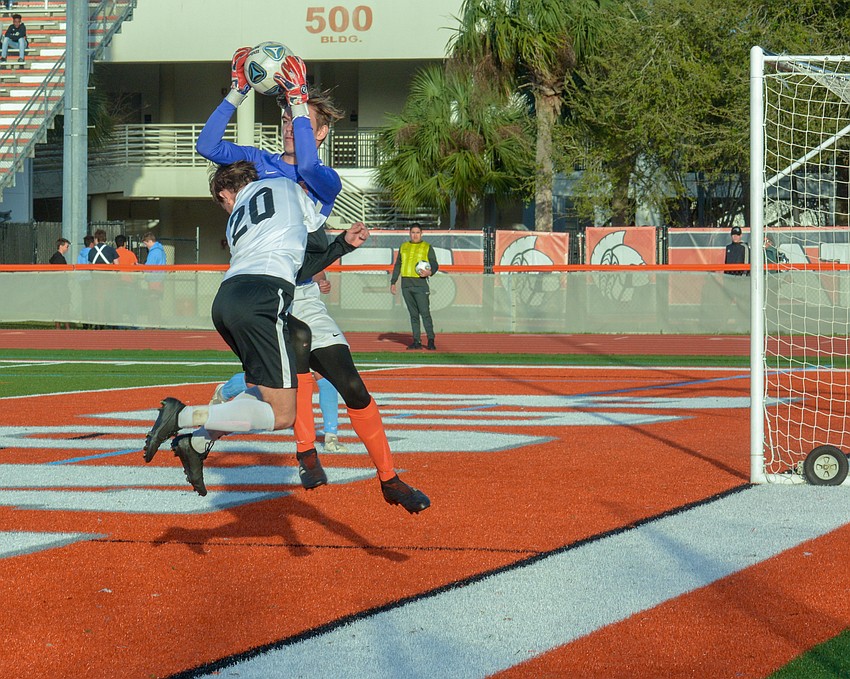 Sophomore midfielder Aiden Holzborn runs into Boone goalkeeper Matthew Cullen on a header attempt.