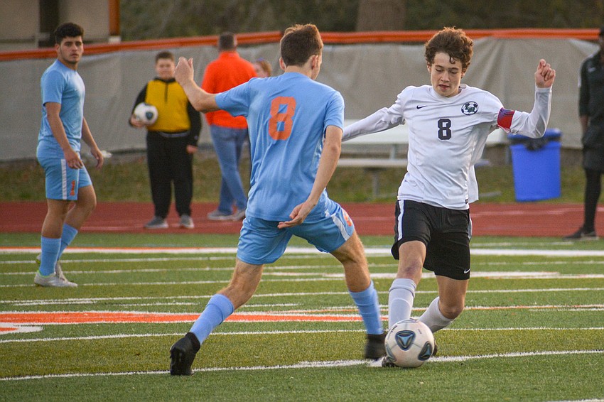 Mustangs senior Jacob Jordan (white jersey) pokes a ball away from Boone junior Ian Haslacker.