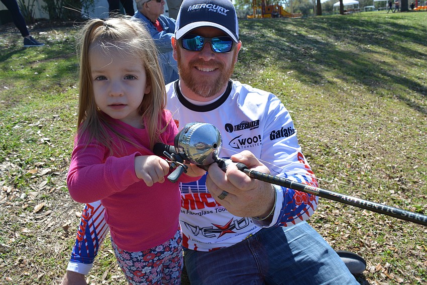 Two-year-old Adeline Giella, of Parrish, visits her dad, Kyle Giella, who taught children to cast and also brought his boat for children to see.  He is a competitive fisherman.