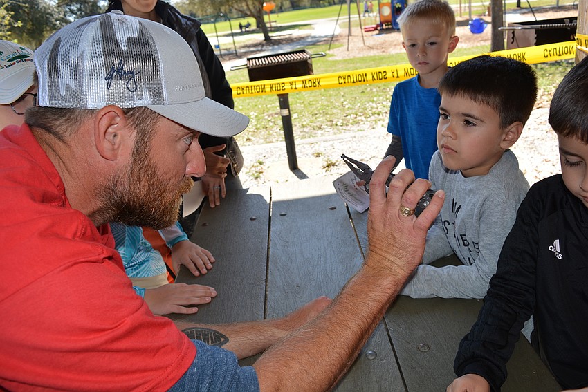 Lakewood Ranch Anglers Club member Chris Crampton shows 6-year-old Francesco Guillermoni how to open the weight and connect it to the fishing line. Guillermoni said he needed to see it another time.