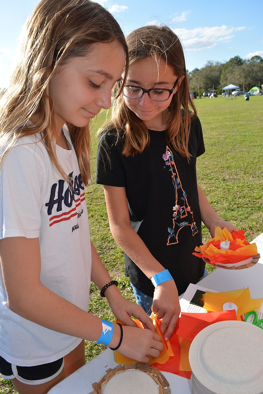 Lakewood Ranch's Maya and Julia Griffin create a campfire craft with a battery-powered candle, a paper plate and tissue paper.