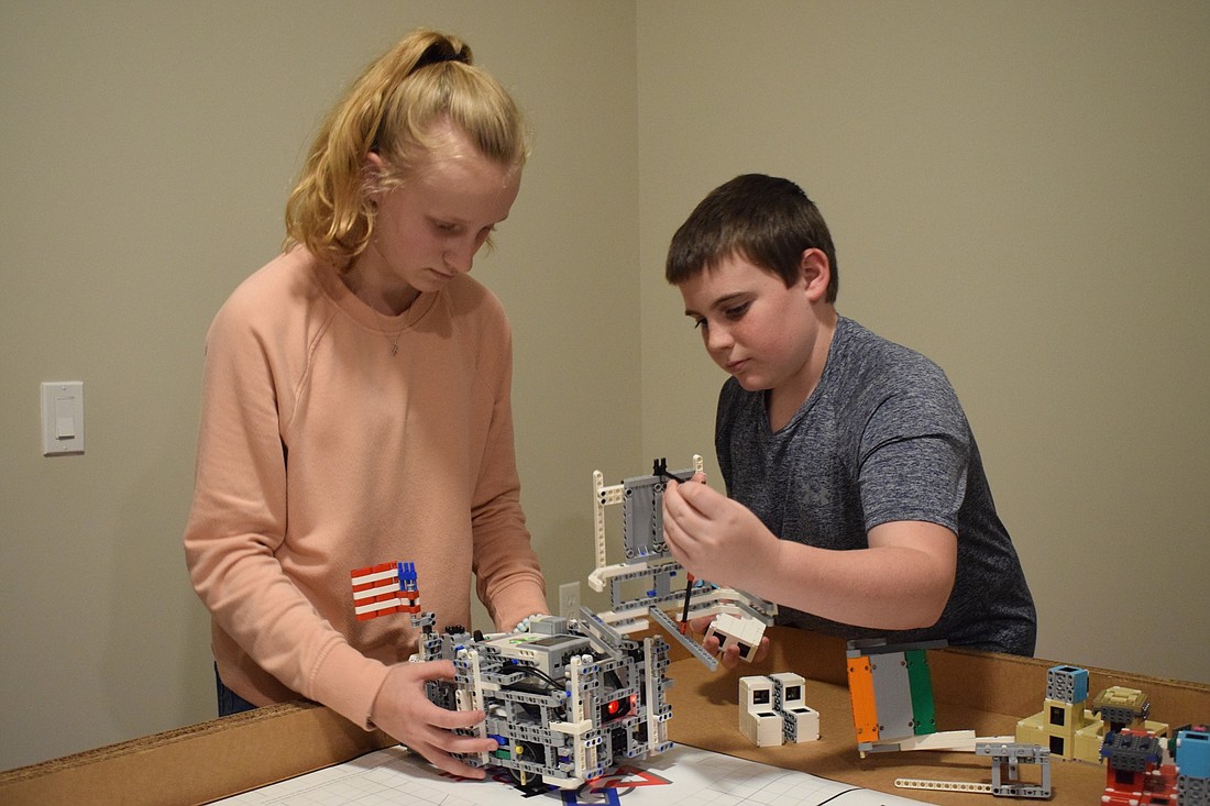 Tess Lippincott and Matthew Goldberg work together to adjust the setting of their robot and add attachments to complete a mission.