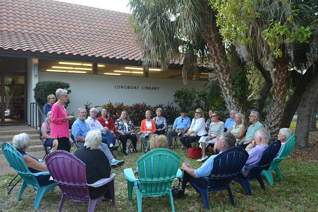 Longboat Library president Mary Baker (standing, wearing pink) speaks to members of the Rotary Club of Longboat Key during a social event Tuesday evening at Longboat Library.
