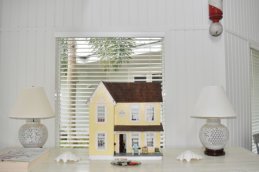 An old dollhouse sits on a table near the home's entrance.