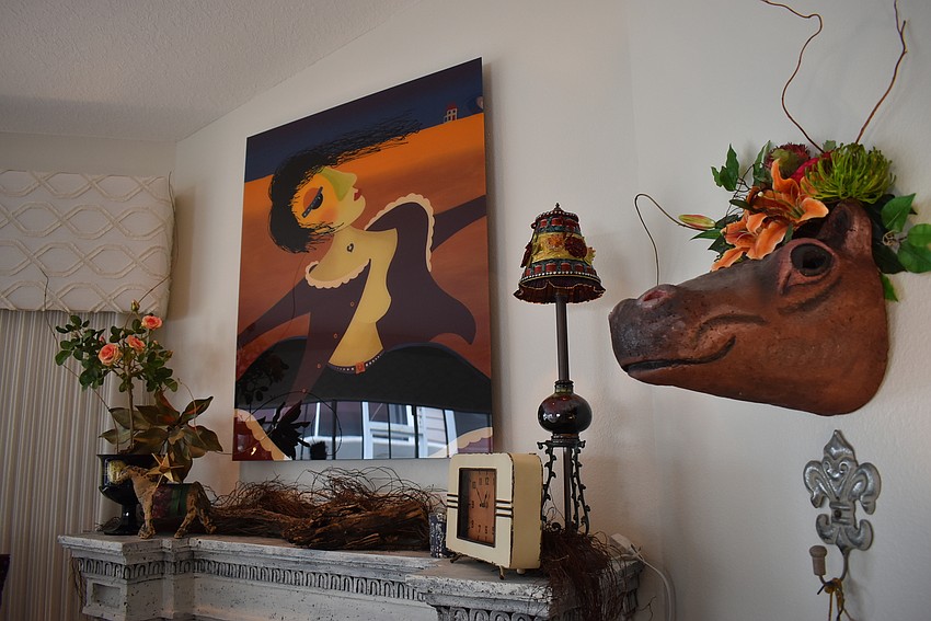 A wacky painting with a green nose is near a hippo head.