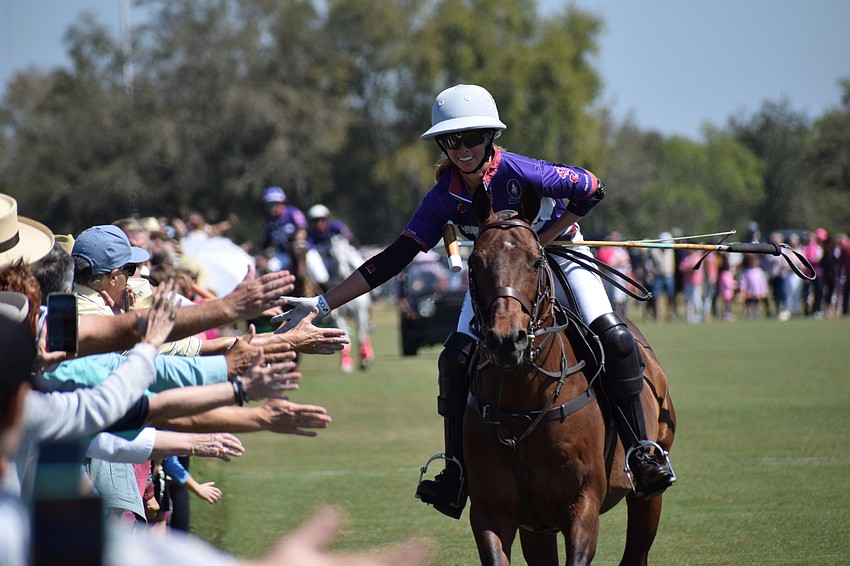 Kylie Sheehan of Avalon Farms races along a line of fans, giving out high-fives before the action at the Sarasota Polo Club.