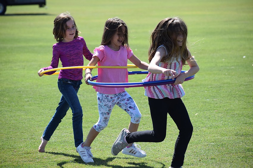 East County's Jaclynn McNeal, 8, Lakewood Ranch's Carly Guido, 7, and Lakewood Ranch's Sara Downs, 9, enjoy a run across the polo field with their Hula Hoops before polo action began.