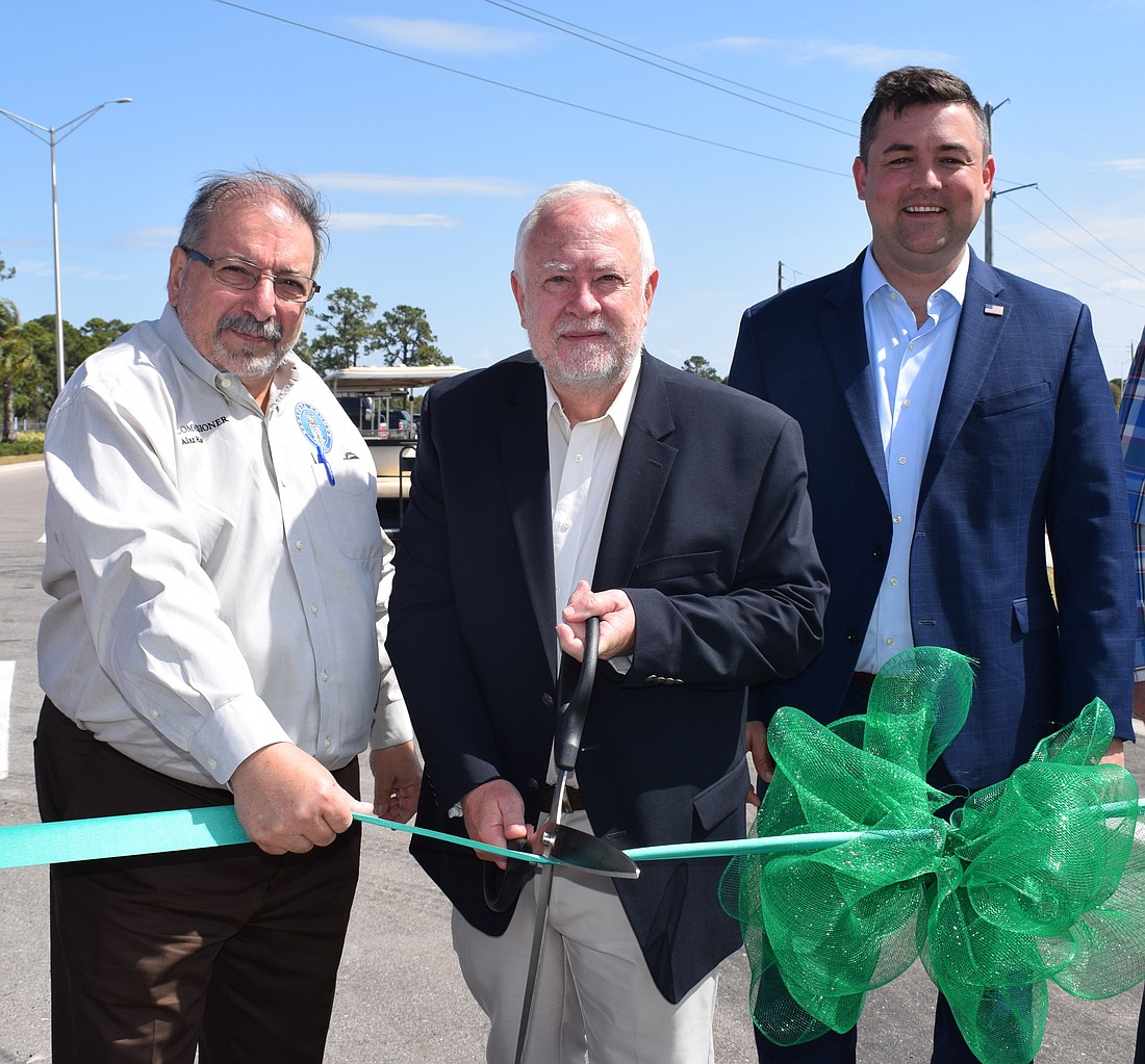 Sarasota County Commissioners Alan Maio and Christian Ziegler stand on both sides of Schroeder-Manatee Ranch President and CEO Rex Jensen, who cuts the ribbon to open the Lakewood Ranch Boulevard extension March 2.