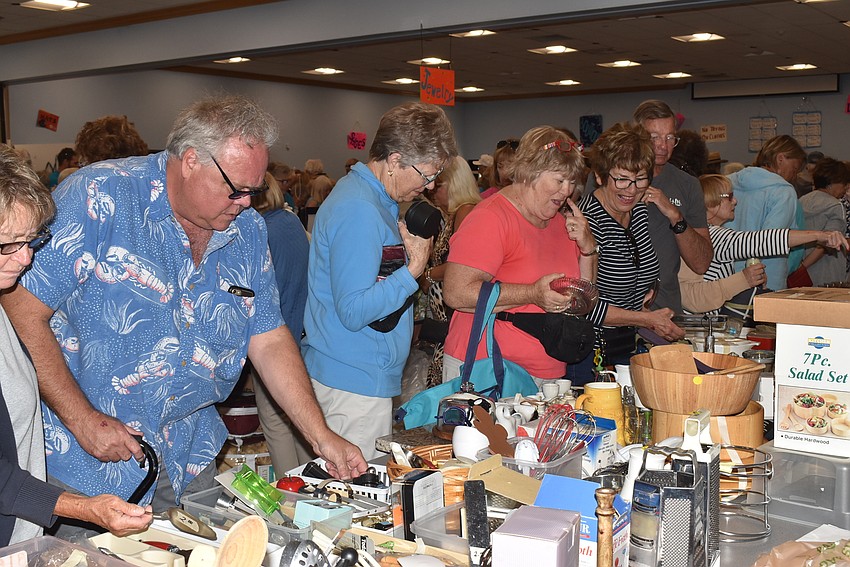Shoppers line up at tables to browse as much as possible.