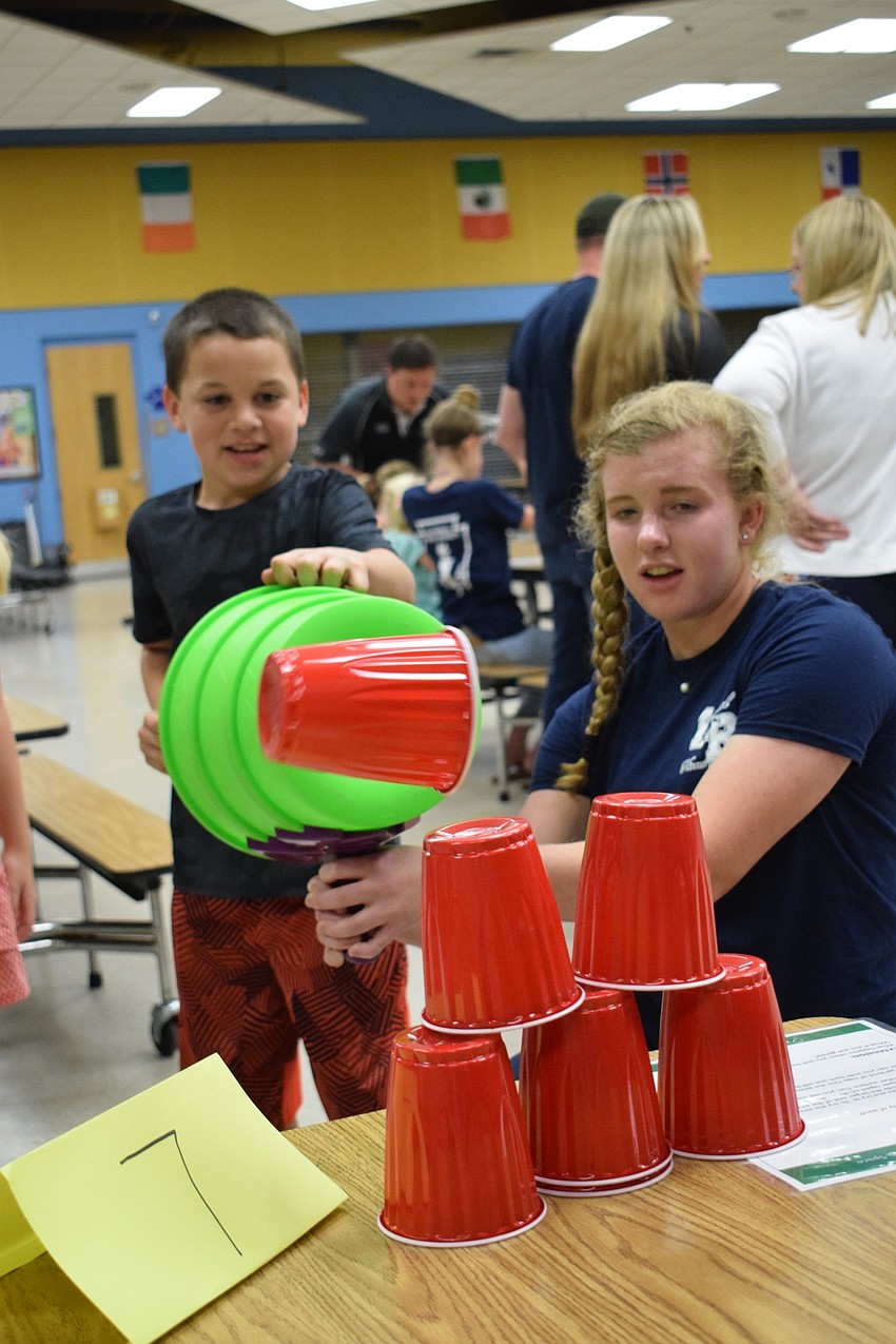 Matthew Vajanyi, a fourth grader, uses an air launcher to blow down cups with the help of Lauren Beck, a junior at Lakewood Ranch High School.