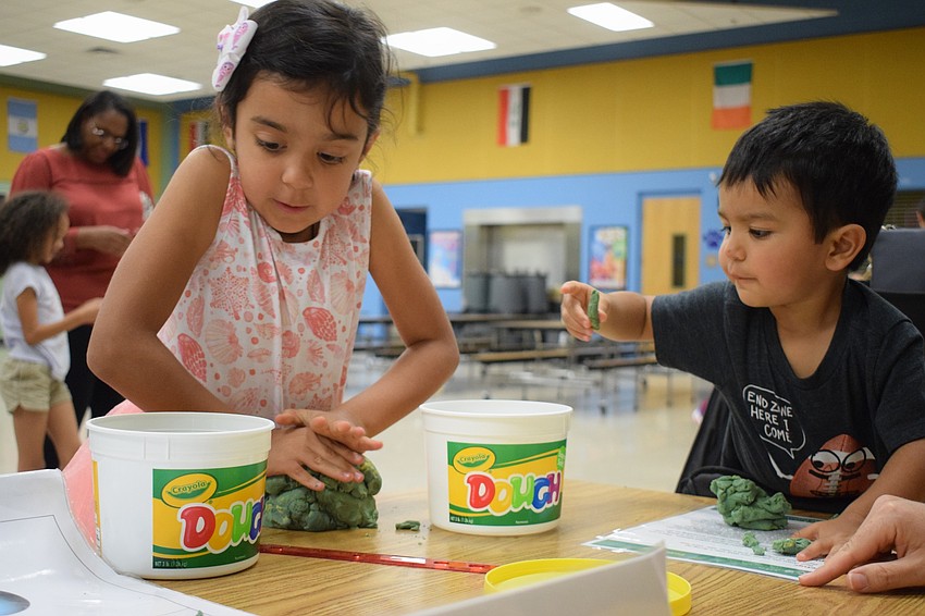 Gabby Perez, a kindergartner, and her 1-year-old brother Zeke use Play-Doh to make planets. 