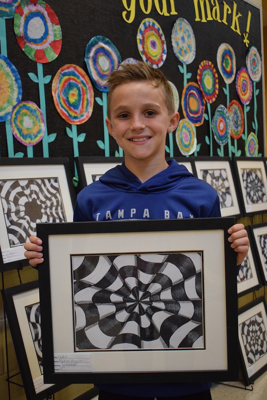 Macklin Higgins, a fifth grader, shows off his art work. Higgins made an illusion as his art project.