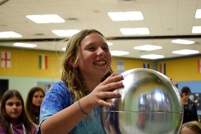 Fourth grader Layna Dorman's hair starts to stand up while touching a Van de Graaff generator, which is creating static electricity. 