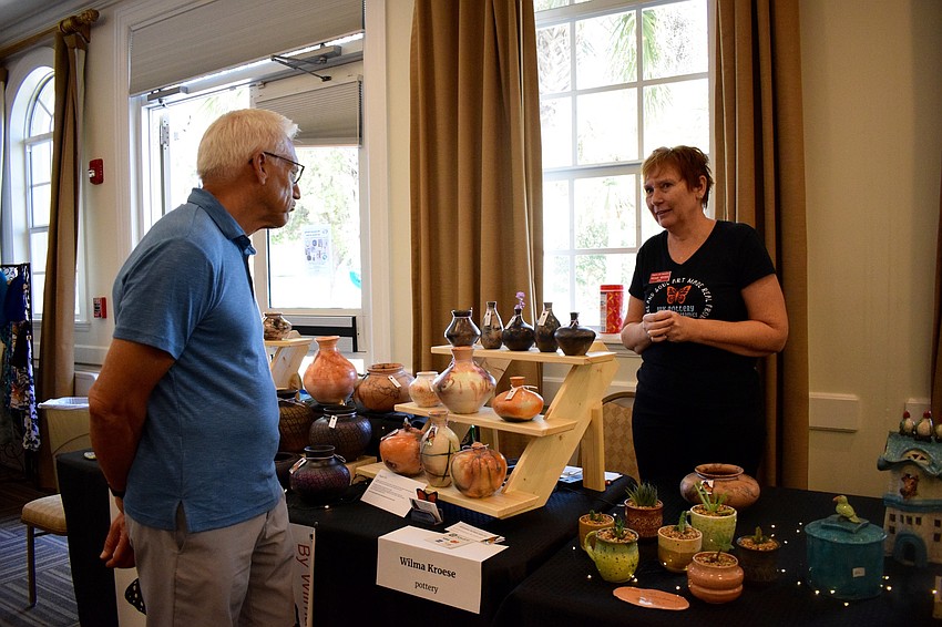Nick Hamp, who is visiting from Clarkston, Michigan, talks to artist Wilma Kroese about her pottery.