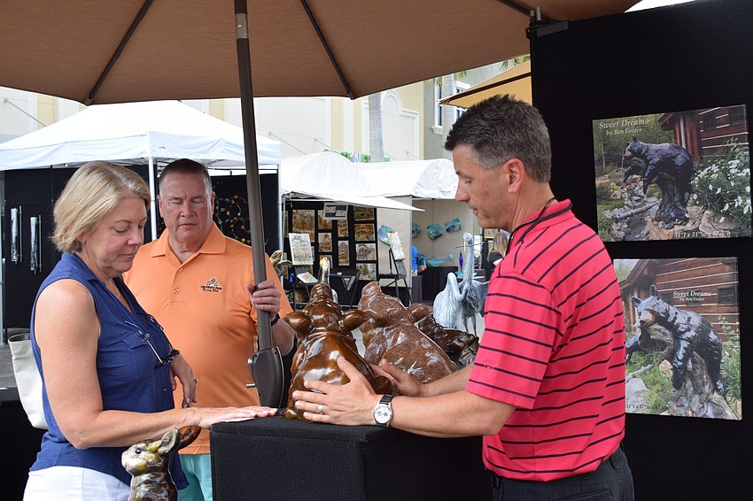 Jan and Terry Monteverde, who are University Park Country Club residents, talk to artist Ben Foster about his bronze sculpture pig. 