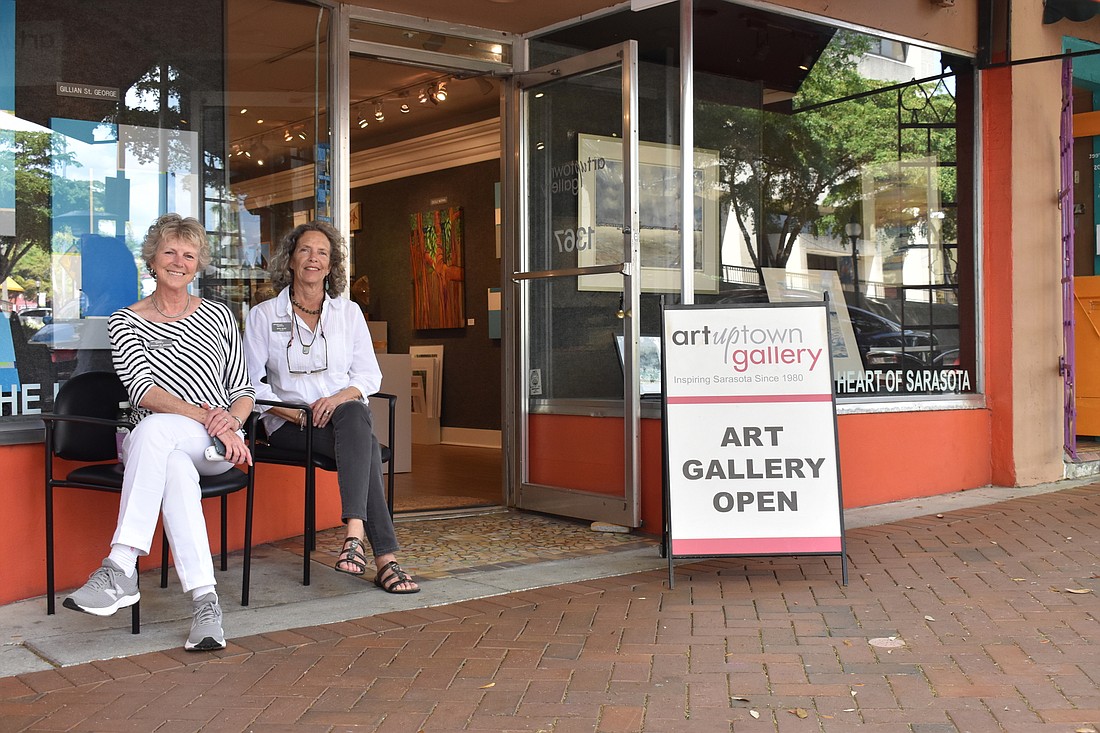Gillian St. George and Rita Rust decide to relax in the late-afternoon breeze Saturday outside Uptown Gallery. Walkthrough traffic had not been significantly off that day they say. (Photo by Klint Lowry)
