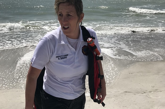 Longboat Key Fire Rescue Department deputy chief Sandi Drake walks ashore after rescuing a man and his teenage son from a rip current March 6 near Longboat Key Club. (Photo courtesy of the Longboat Key Fire Rescue Department)