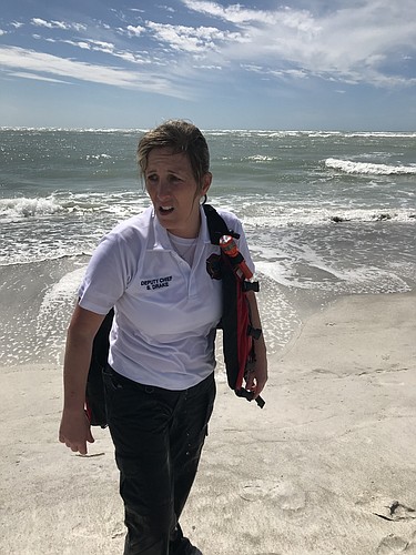 Longboat Key Fire Rescue Department deputy chief Sandi Drake walks ashore after rescuing a man and his teenage son from a rip current March 6 near Longboat Key Club. (Photo courtesy of the Longboat Key Fire Rescue Department)