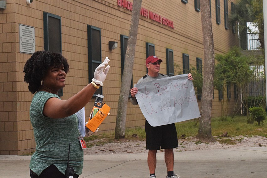 Braden River Middle School Principal Kimberlain Zenon-Richardson and U.S. history teacher John Wolfe greet families as they come to pick up devices for online learning or instruments.
