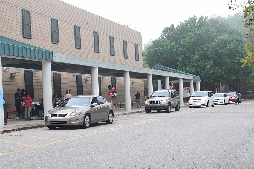 Families line up for curbside device pick-up at Braden River Middle School.