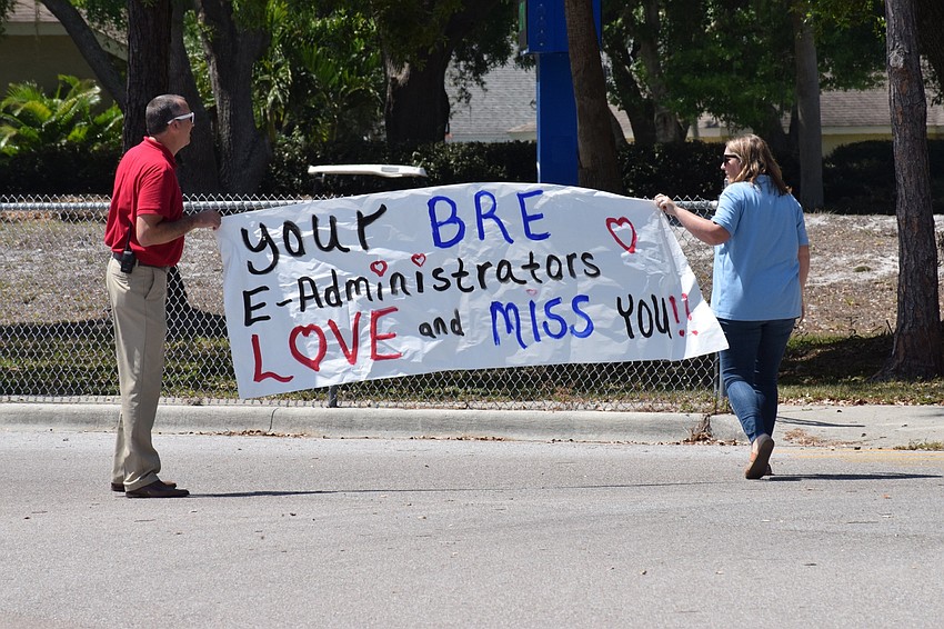 Braden River Elementary School Principal Joshua Bennett and Assistant Principal Krista Francies post a banner for families to see as they're leaving the school after the e-learning kickoff parade.