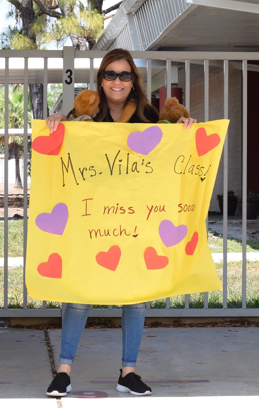 Frances Vila, a kindergarten teacher, holds Marco the monkey and Mr. Bear up for her students to see. 