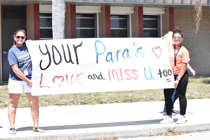 Teri Adams and Kayla Schumaker, paraprofessionals at Braden River Elementary School, hold up a banner during an e-learning kickoff parade at the school.