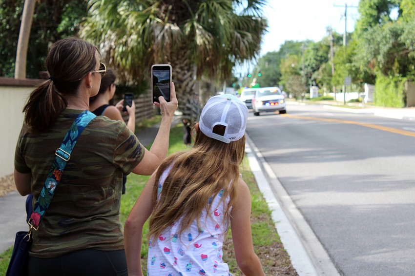 Families line the streets near Southside as teachers drive toward them.