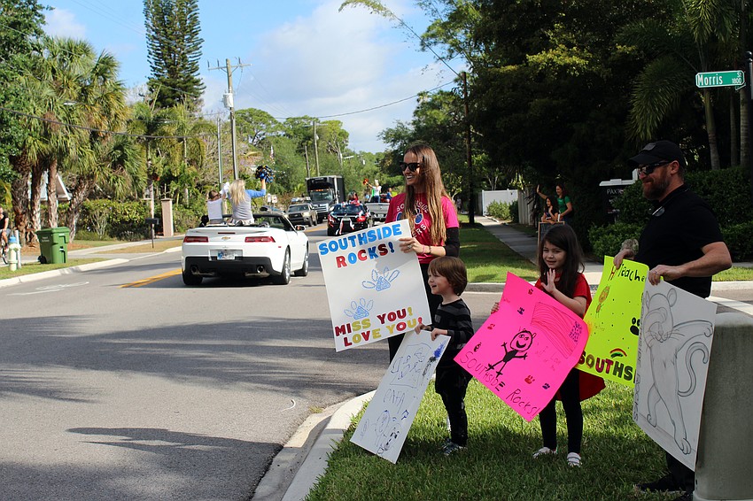 The Rivolta family hold homemade signs as teachers drive by.