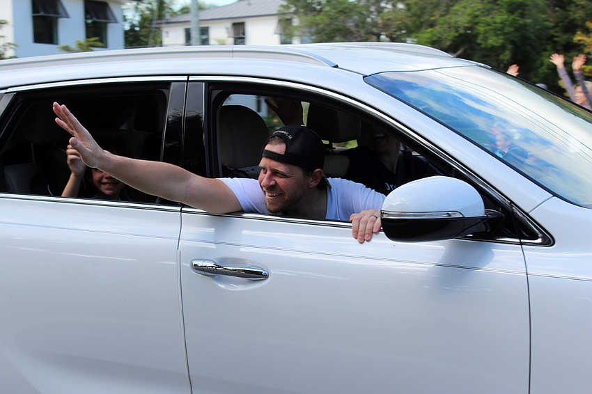 Teachers wave to students as they drive by.