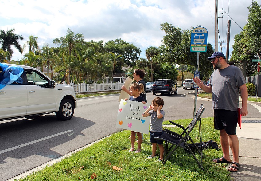 The Howell family cheers on the teachers as they drive by.