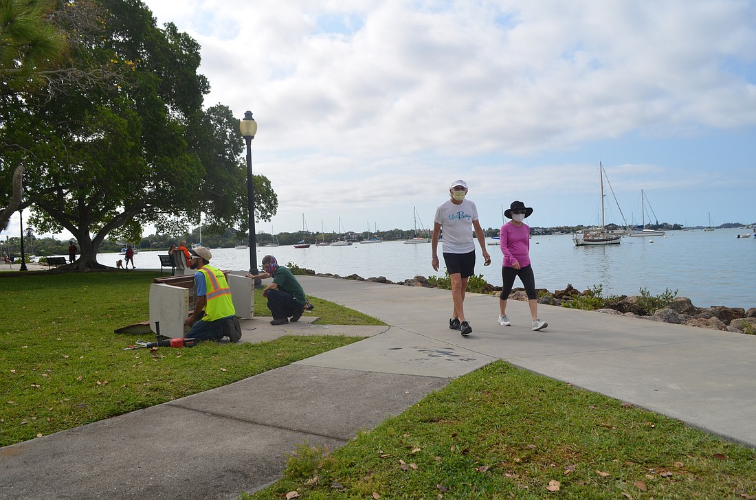 City workers repair a bench in Bayfront Park on Wednesday, April 8. Parks and recreation staff members are among the Sarasotans still working essential jobs during the statewide COVID-19 shutdown.