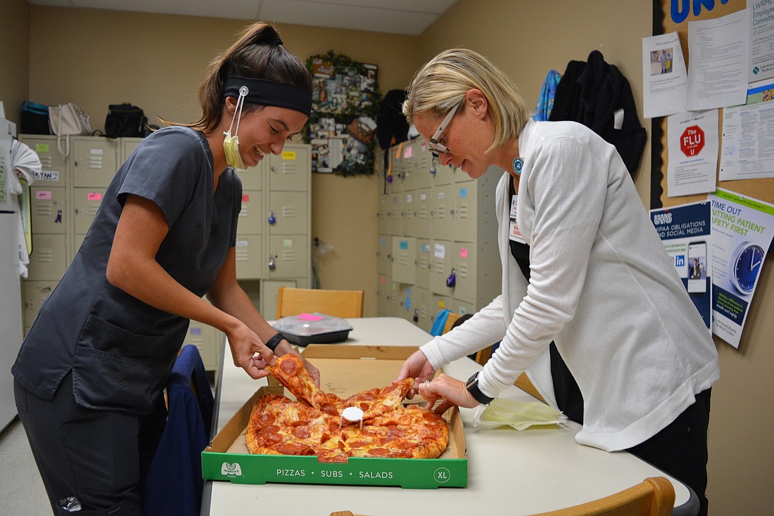 Nurses Noelle Clark and Shannon Zies take a break for pizza from Marco&#39;s Pizza. They say such donations from the community make them feel appreciated and help alleviate stress.