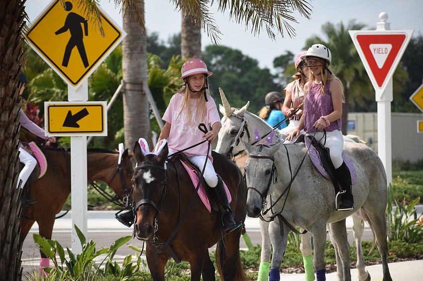 The Sarasota Polo Ranch's Hanna Hornung, 12, guides her horse down a sidewalk at Grand Living.
