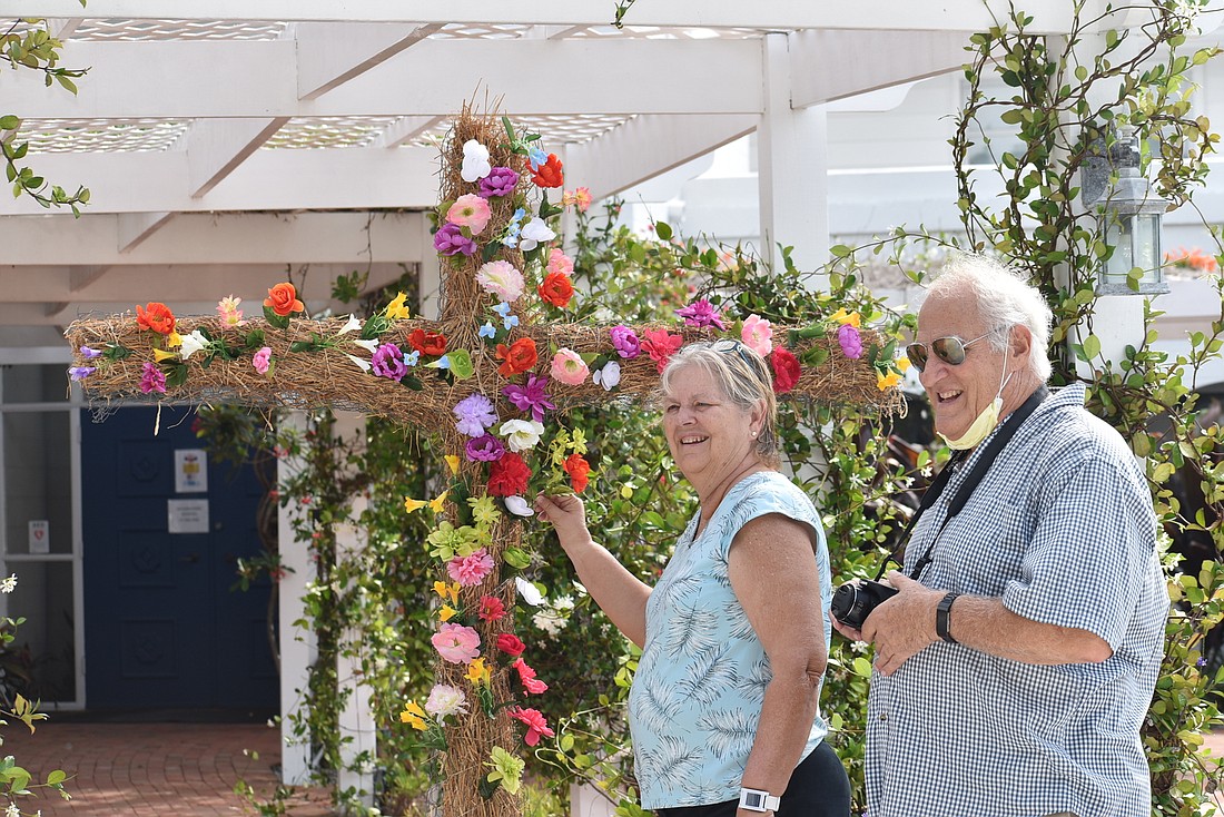 Donna Hefner and Greg Fiore place flowers on the cross at Longboat Island Chapel