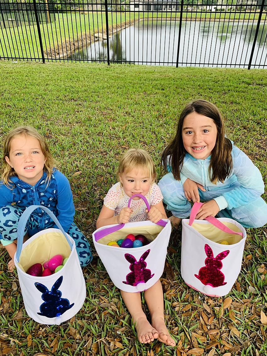 Clara Heuss, 6; Jolene Heuss, 3; and  Anna Heuss, 9; get ready to count their eggs after they finished their hunt in Mill Creek.