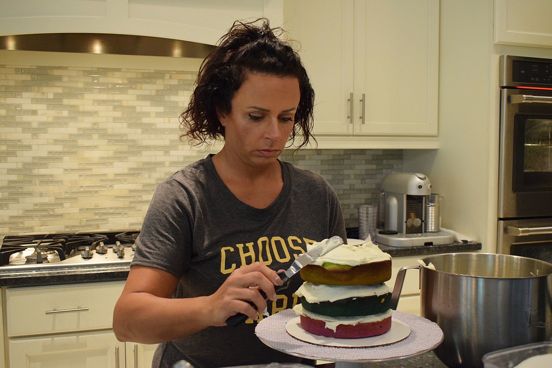 Valerie Demino layers her rainbow cake. Demino has delivered cakes to health care workers, teachers and friends.