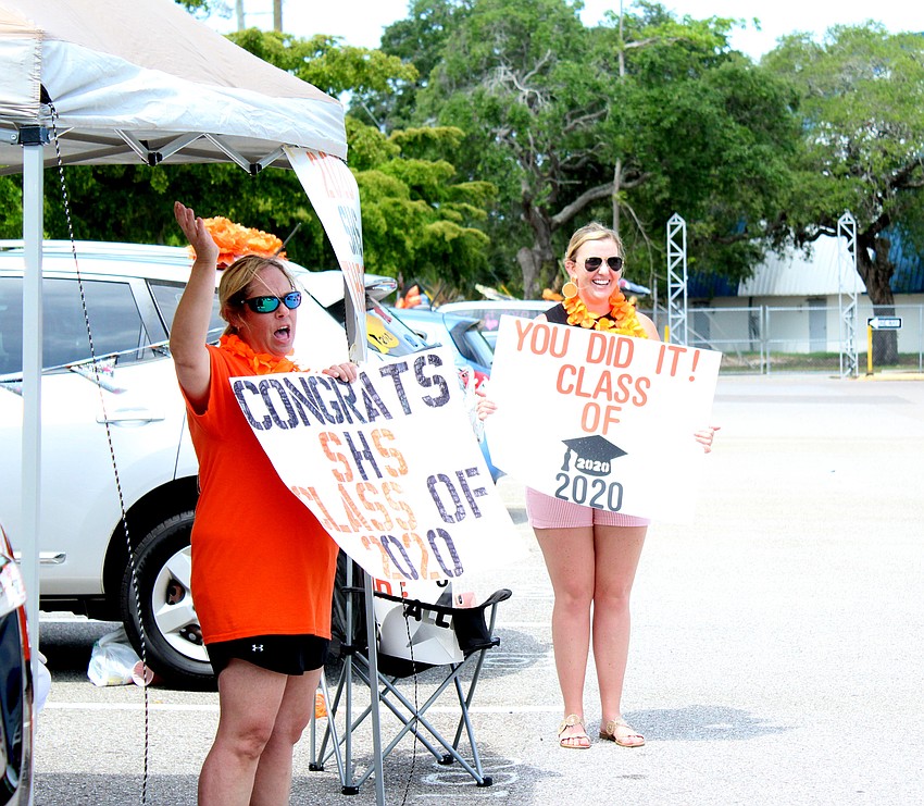 Sue Graham and Alana Hodge greet students as they pull into the parking lot.