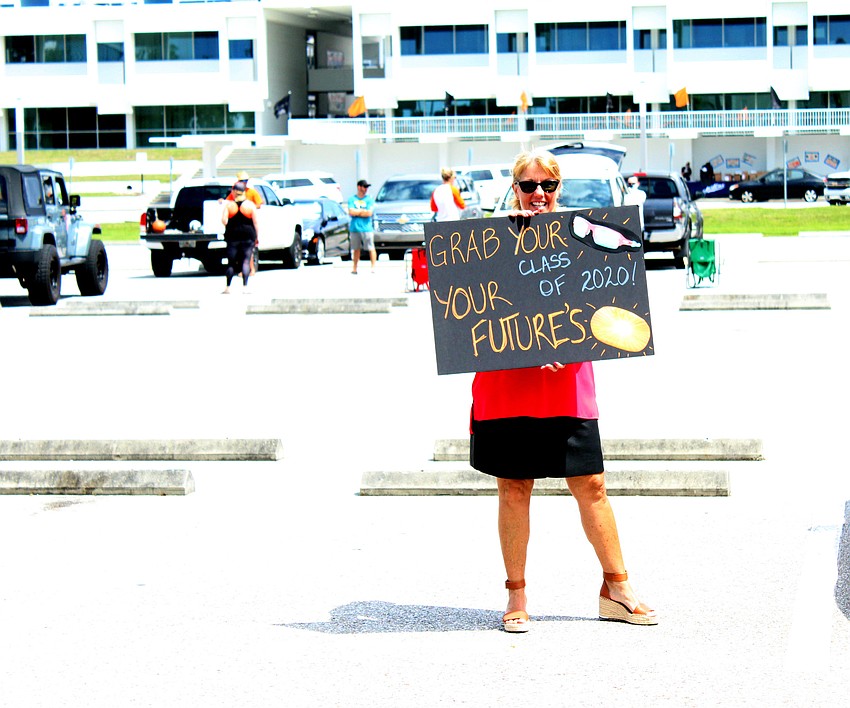 Wendy Kuhns waves her sign for students.