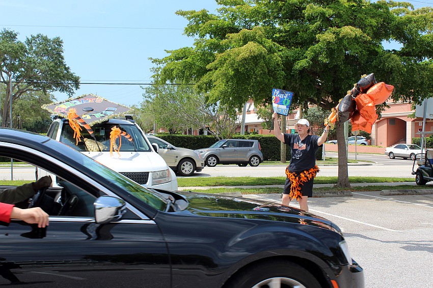 Valerie Moffitt waves balloons in front of her car made to look like a graduation cap.