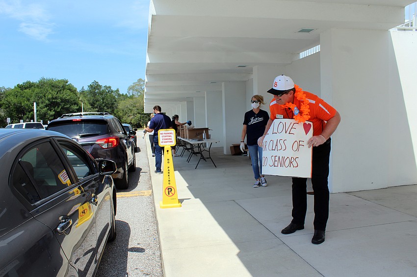 Principal David Jones talks to each student as they wait to pick up their graduation caps and gowns.