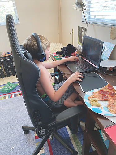 A modern-day, distance-learning fourth grade student â€” headphones, no shirt, pajama pants and pizza. â€œHis dream come true,â€ his mother says.