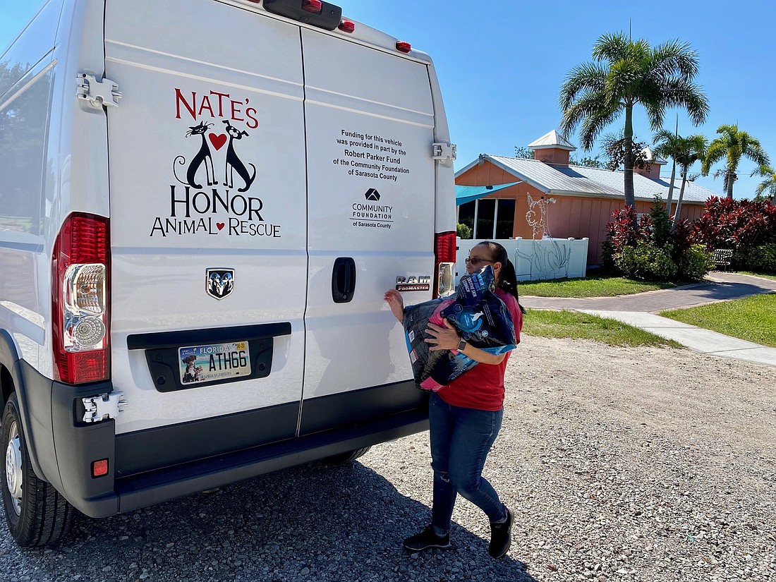 Amy Caron, a staff member with Nate&#39;s Honor Animal Rescue, loads a van with food to deliver. Courtesy photo.