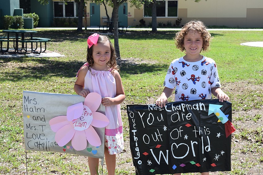 Gilbert W. McNeal pre-kindergartner Catalina Bennett and her brother Thiago, a kindergartner, show off the signs they made for their teachers.