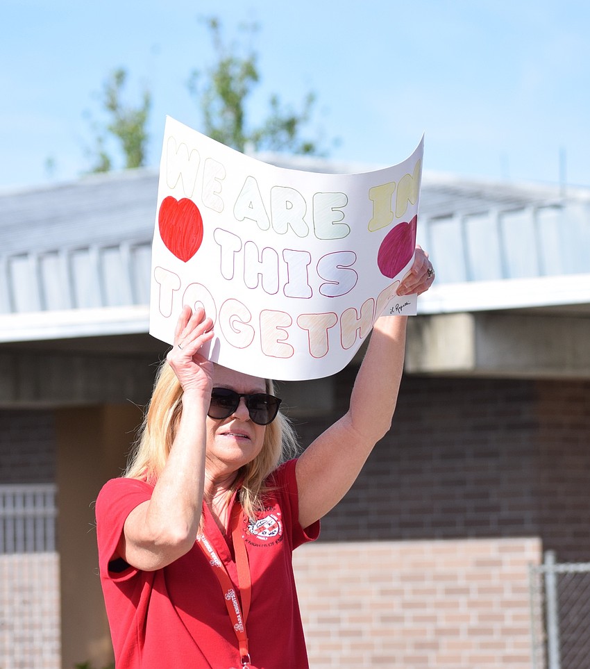 Mary Beth Van Zandt, an exceptional student education teacher at Tara Elementary School, holds a sign up with a message to students driving by during the parade.